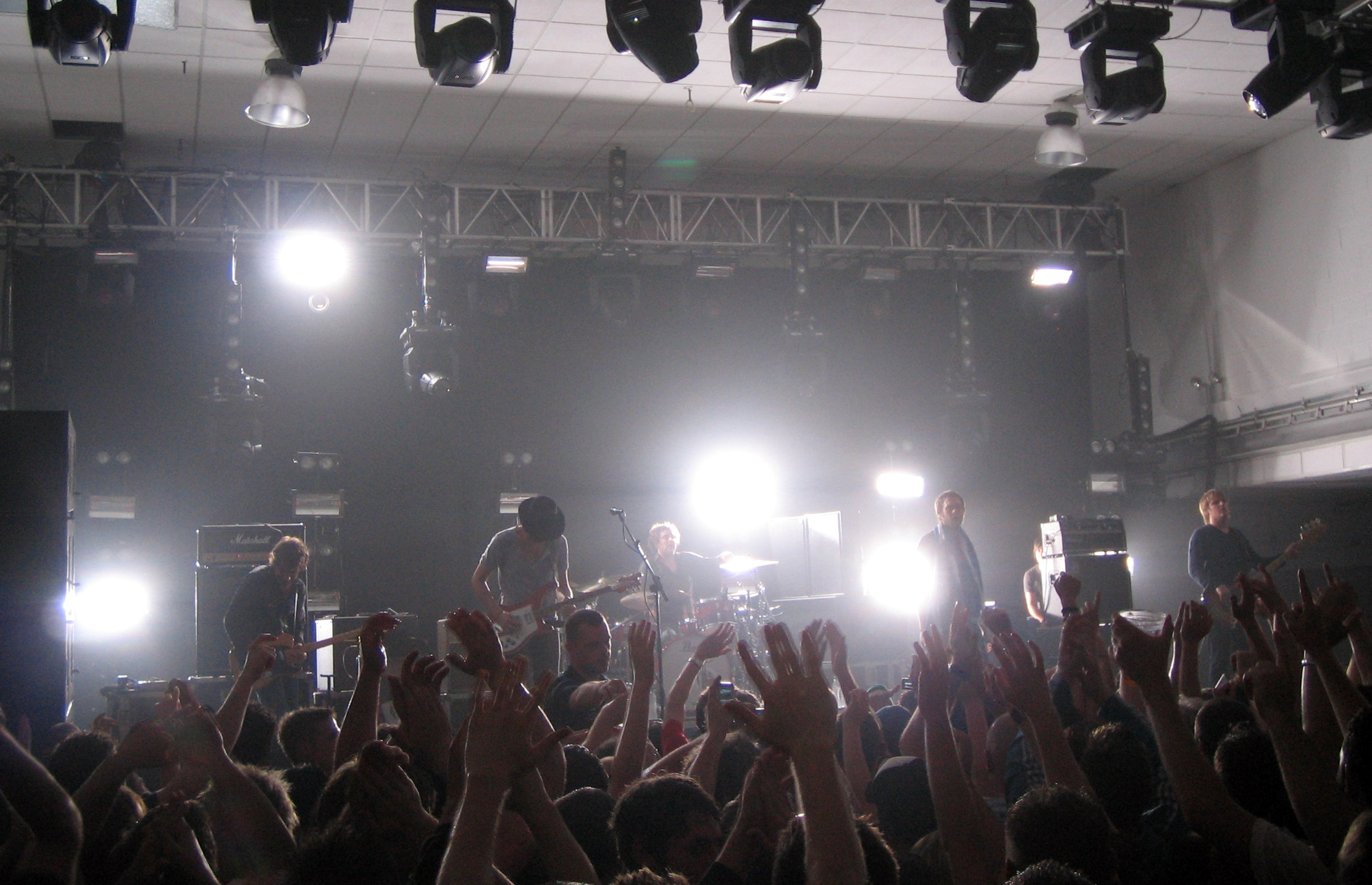 crowd with arms up in front of lights making a music show