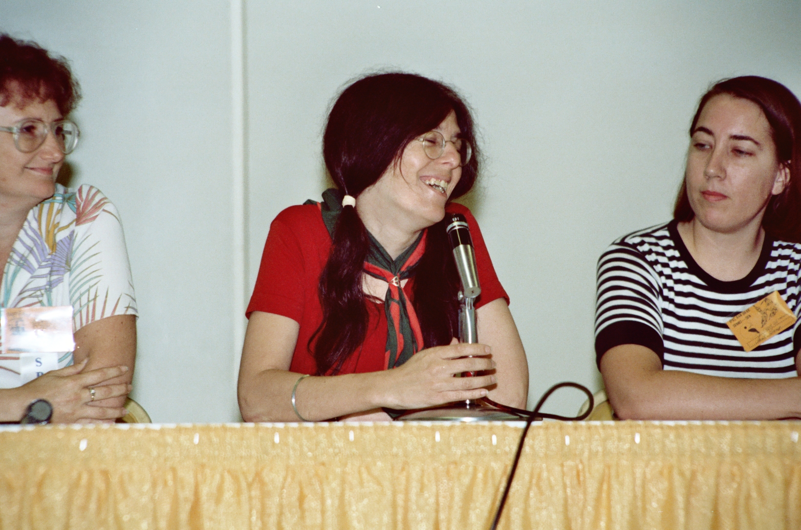 three women sitting at a table with a microphone in front of them