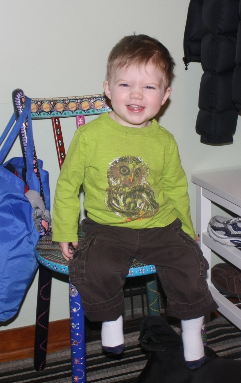 the boy is sitting on a chair with one foot propped against his knee