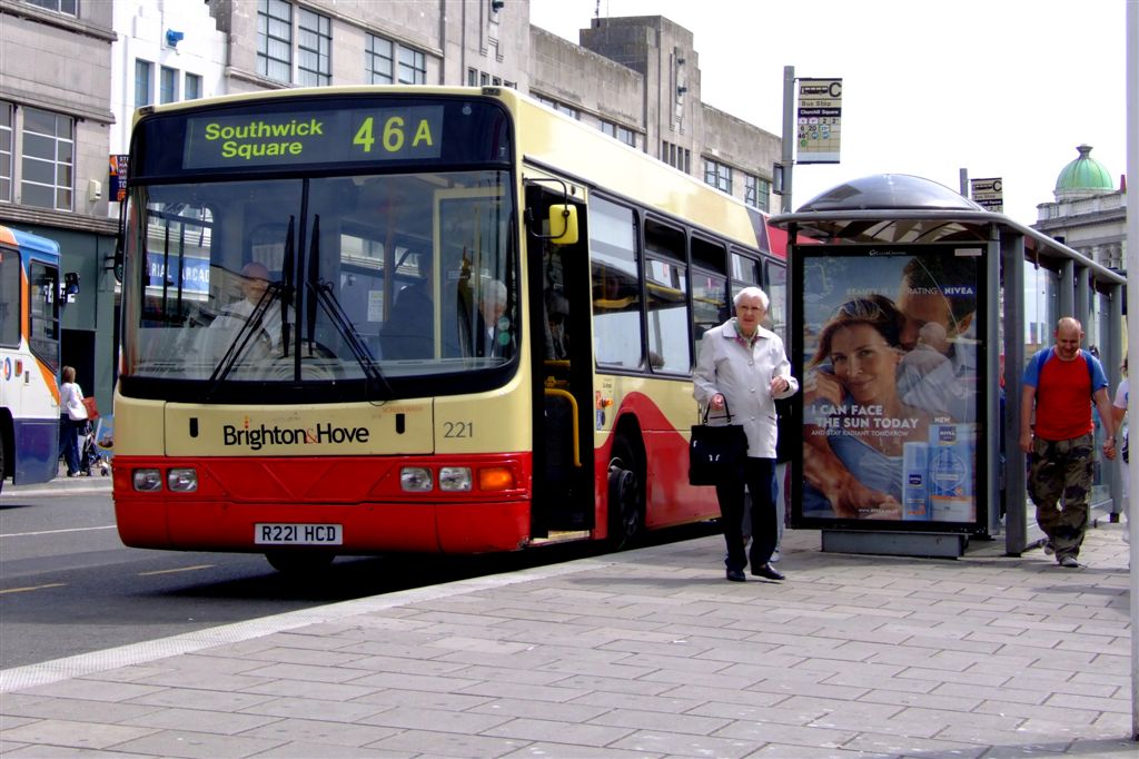 there is a bus parked at the curb in front of two people