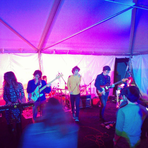 people playing music inside of a tent on stage