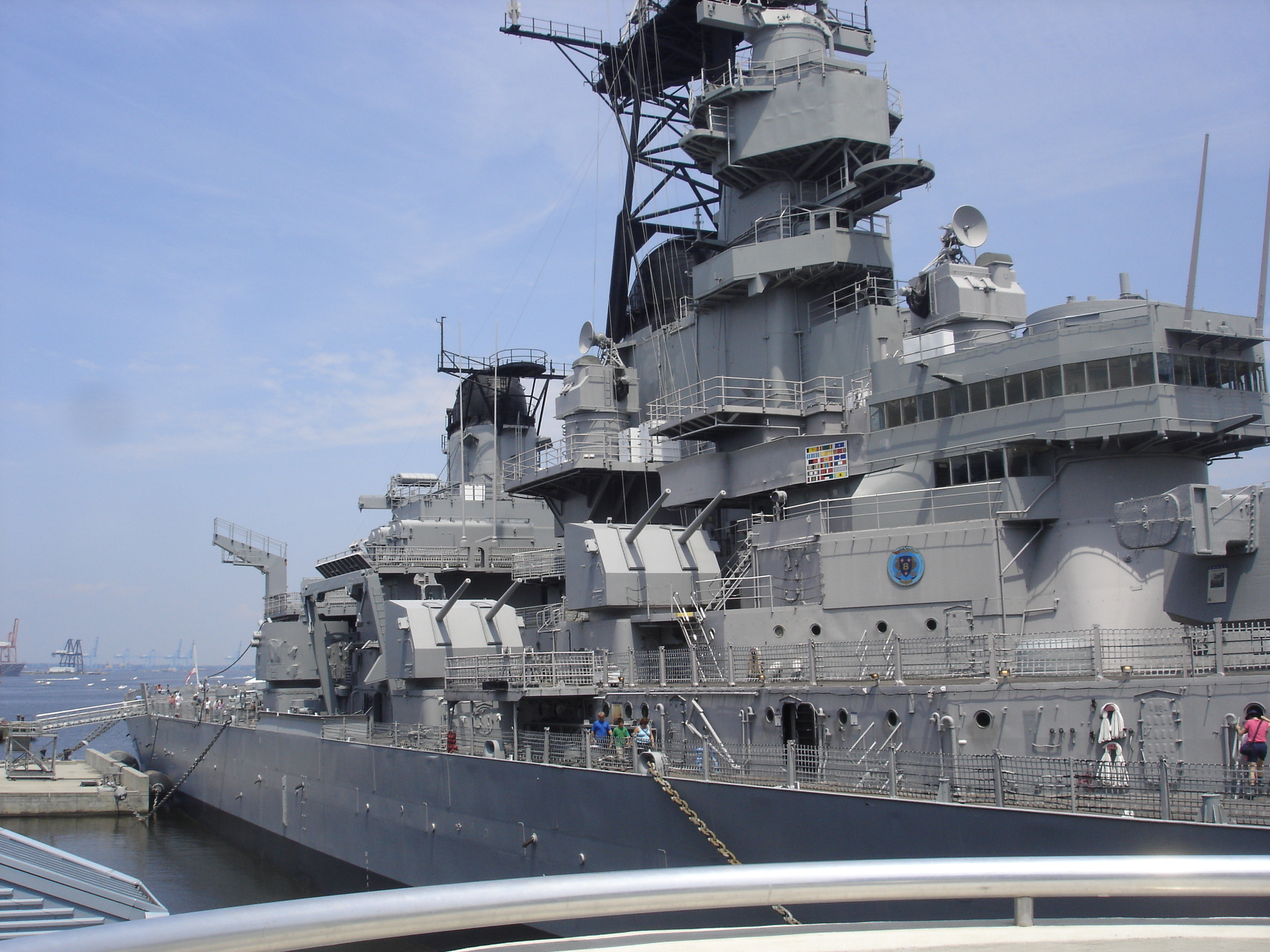 a battleship docked with people on the dock