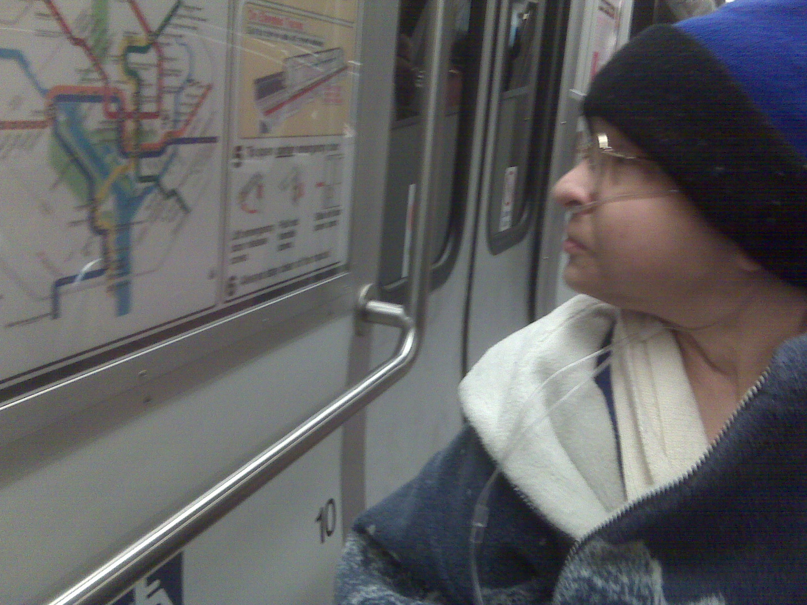 a woman wearing a blue hat looks at the train maps