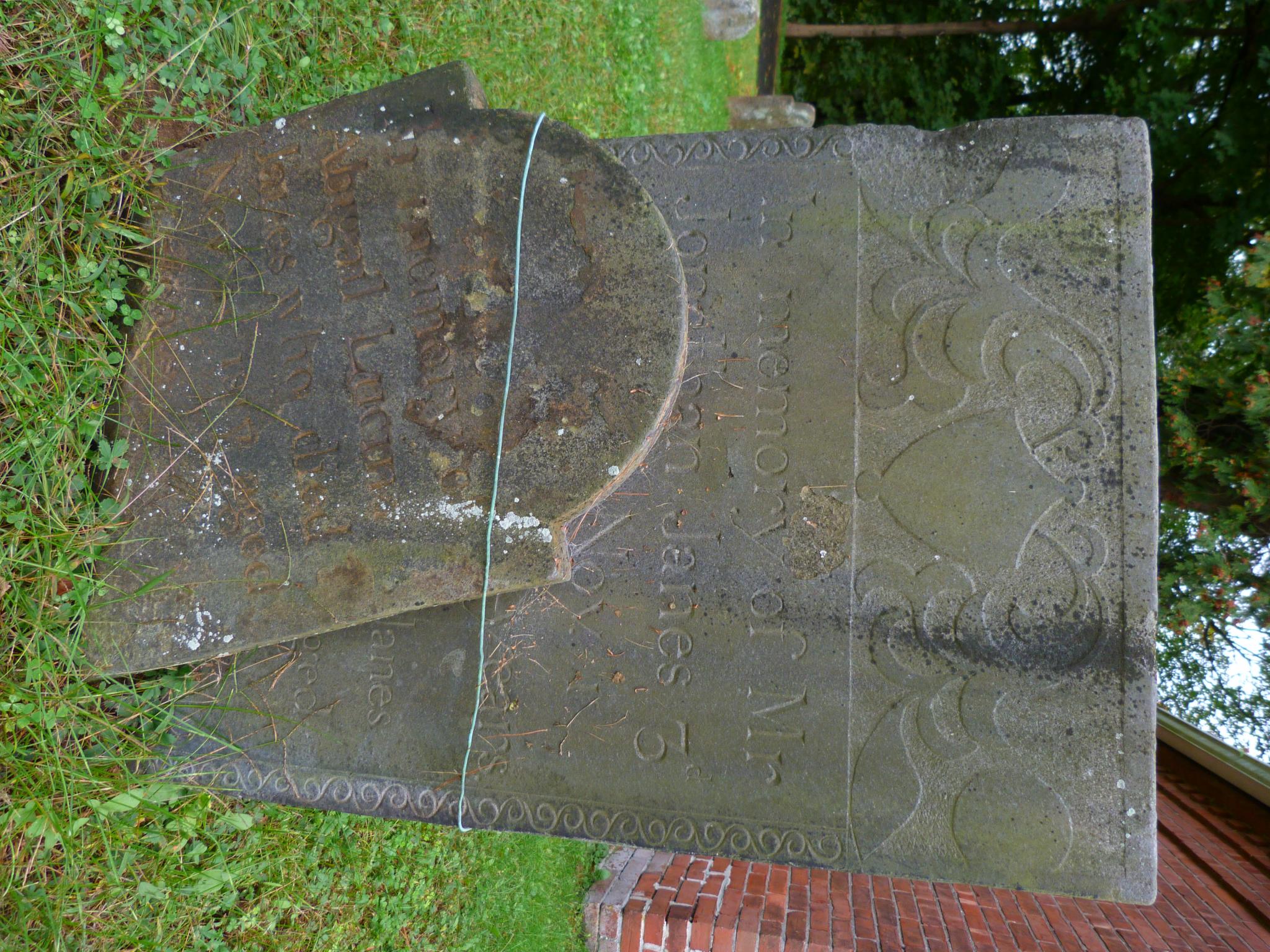 a cement tombstone in a grassy field with writing on it