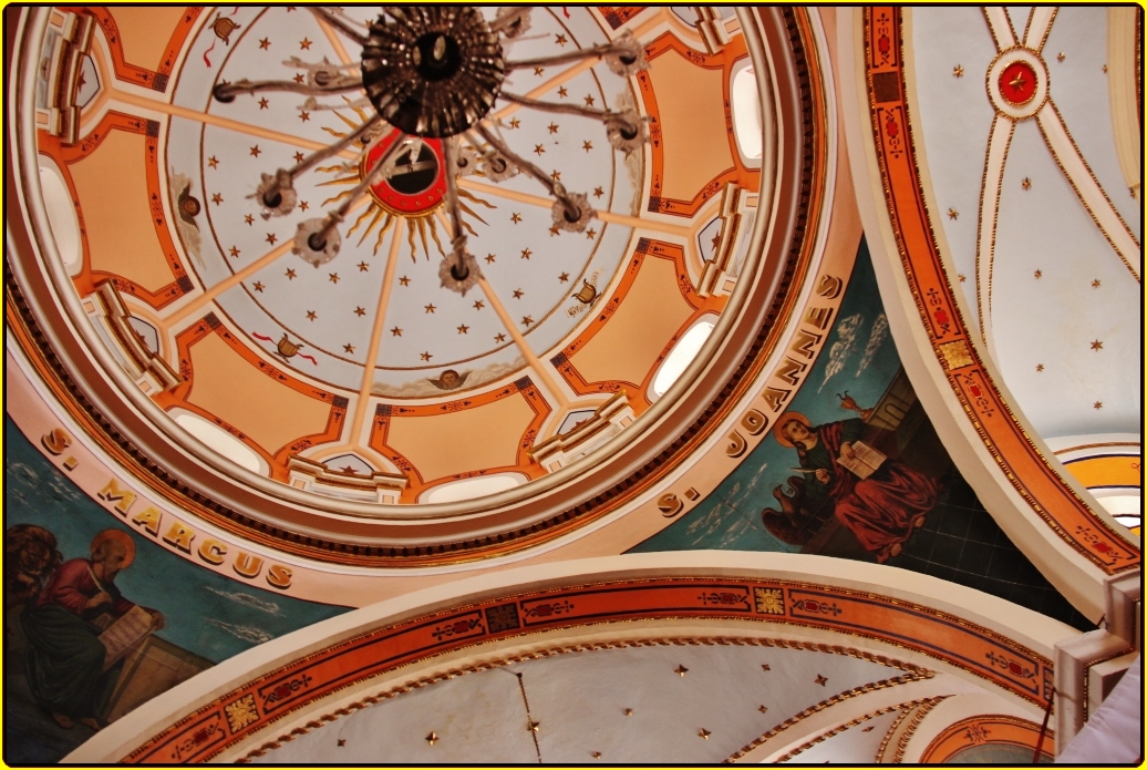 large circular clock mounted inside of a dome with painted ceilinging