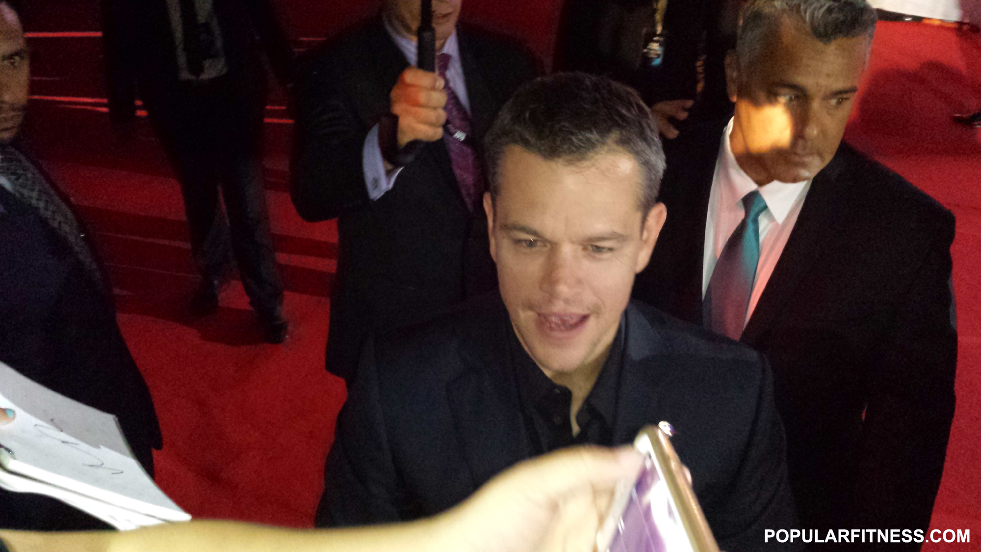 man in suit looking at his cell phone and pointing to the screen