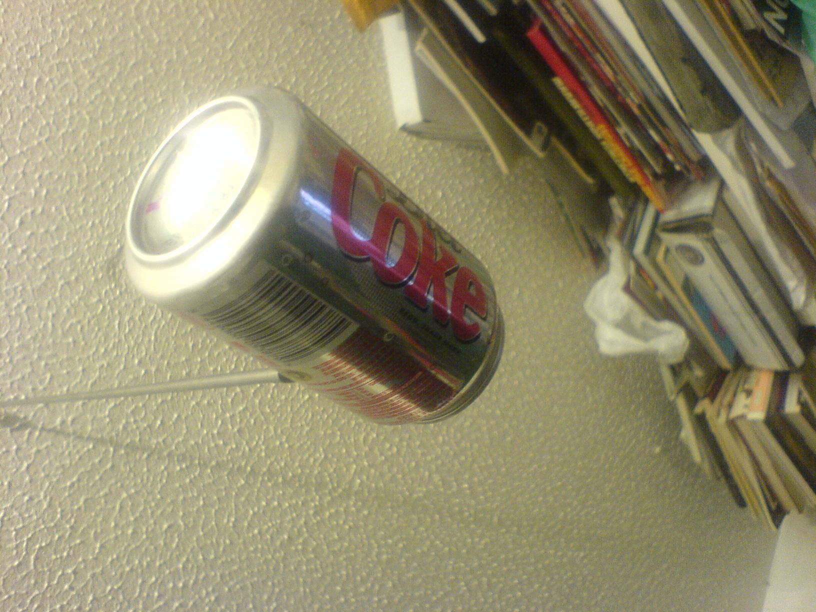 an open can of coke is hanging on the wall