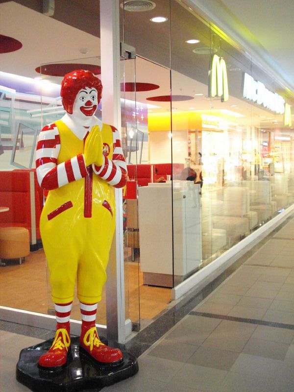 a big statue of a clown on a bench in a mcdonald's