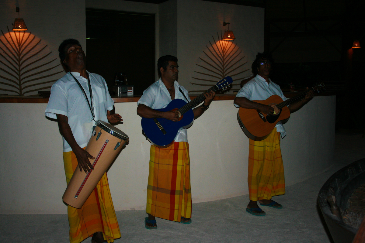 three people wearing yellow and orange with guitars in hand