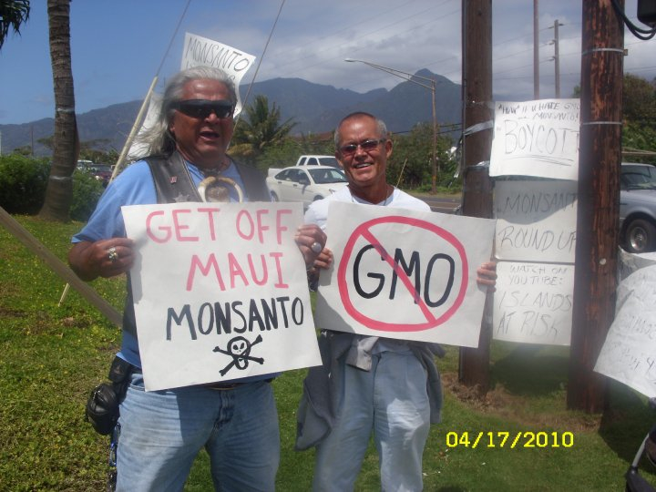 two men hold signs while they protest against monsans
