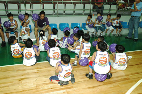 children in uniform sitting on the floor in front of their coach