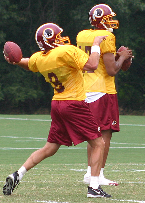 two men in maroon and yellow uniforms, holding a football