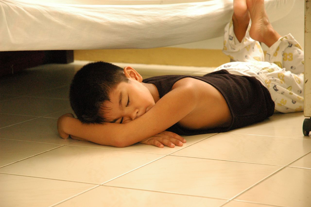 a young child is sleeping on the floor next to a bed