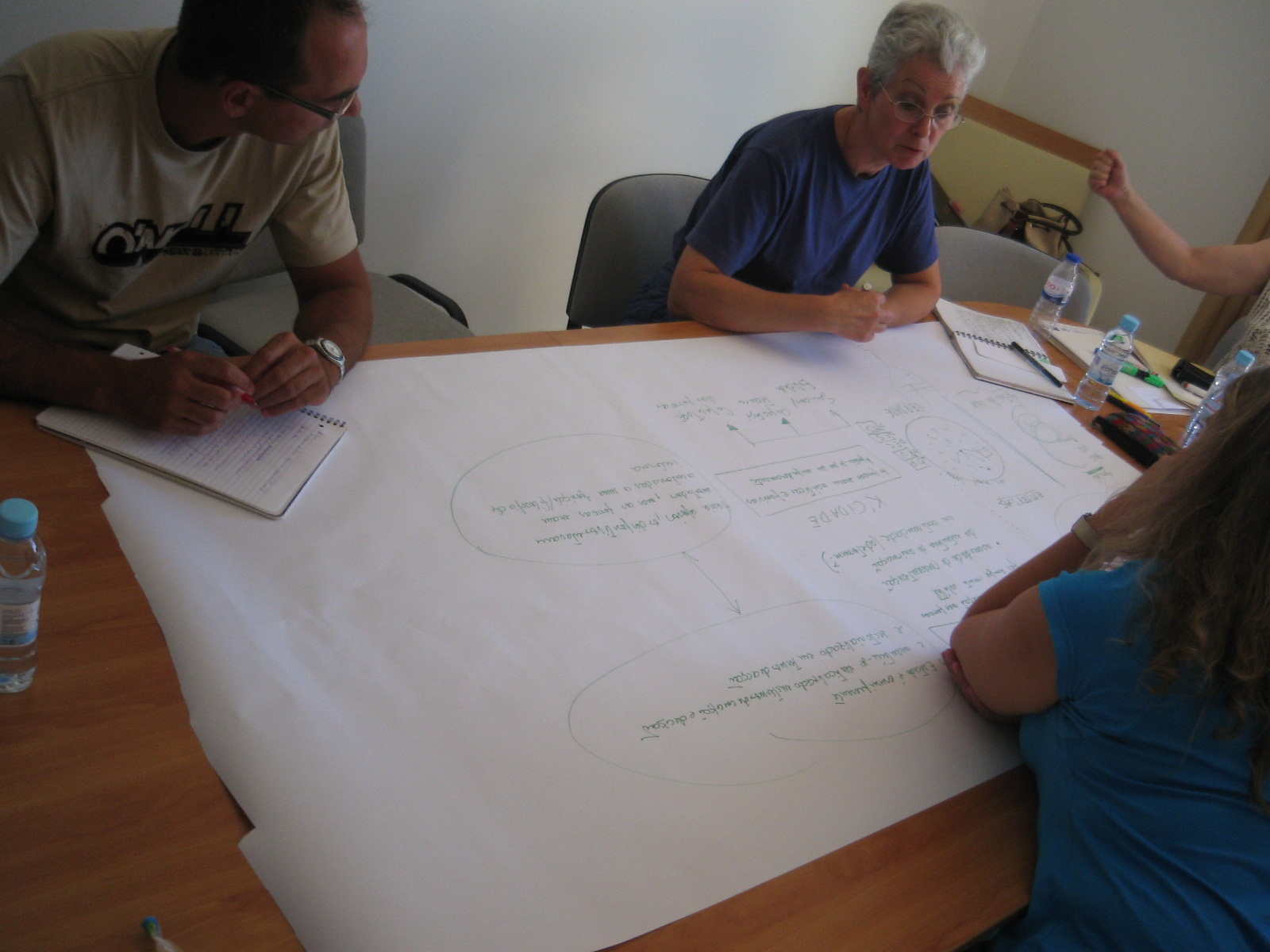 two people are at a wooden table writing on white paper