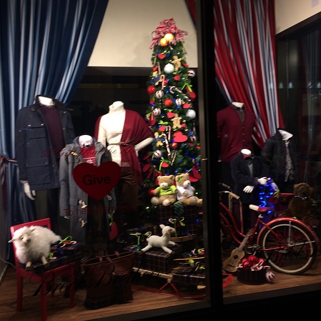 a window is decorated with mannequins and a christmas tree