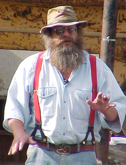 a man with a long beard wearing a hat and suspenders
