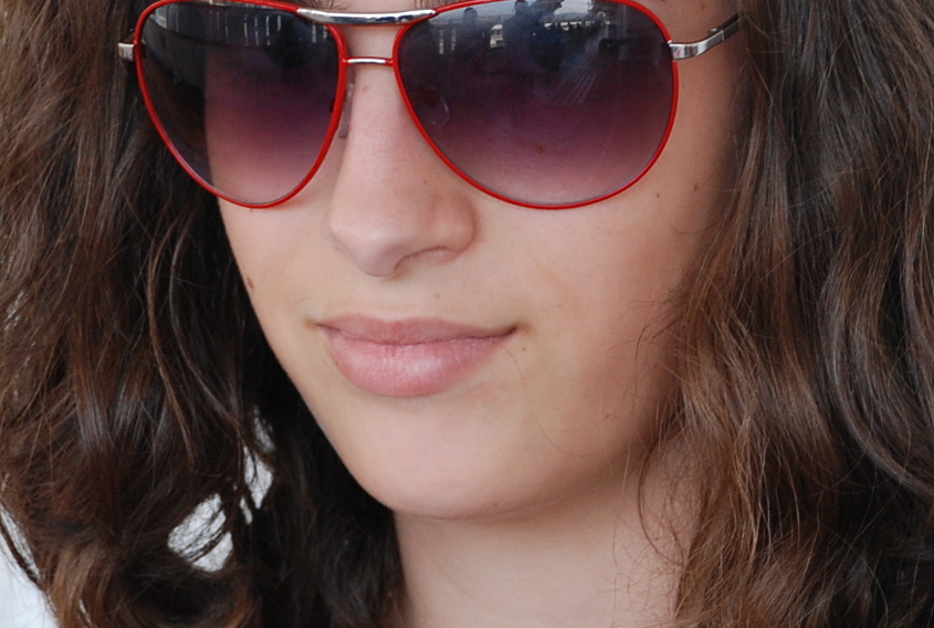 a girl wearing red sunglasses and smiling at the camera