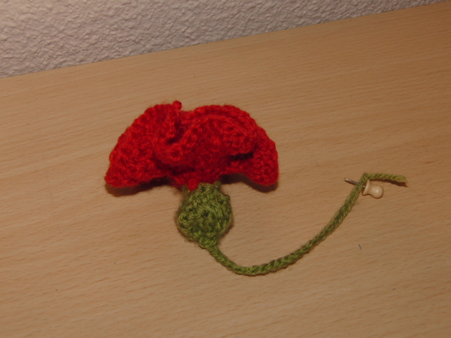 a knitted flower attached to a small wooden stick