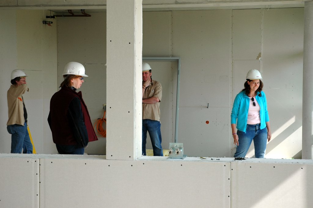 people with hard hats look up from a building construction site