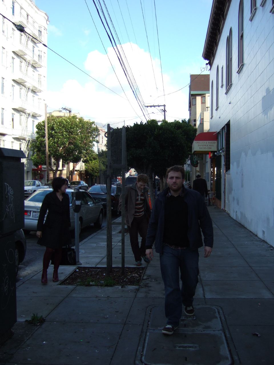 three young men walking down a sidewalk near some tall buildings