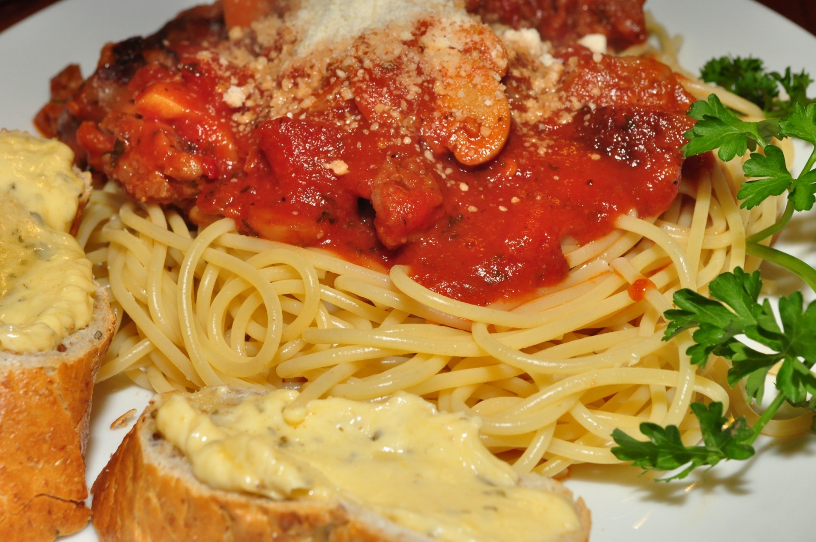 the plate has noodles, meatballs and bread on it