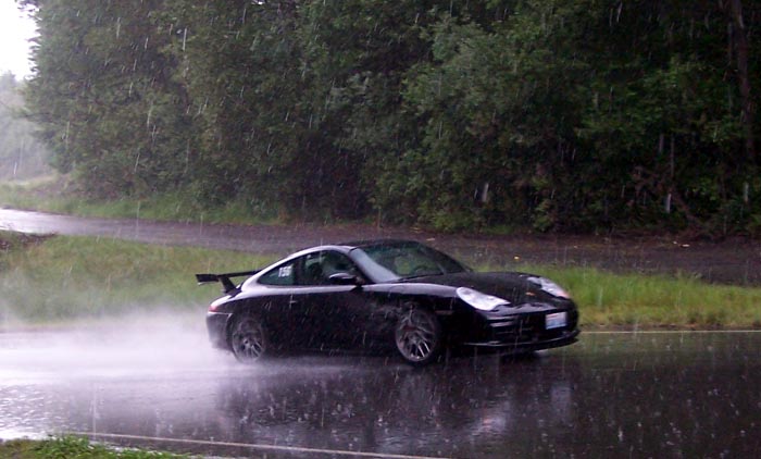 a black car driving down a flooded street