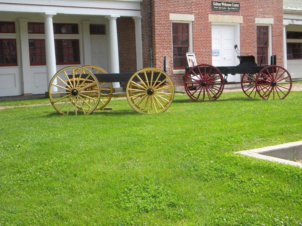 a row of wooden horse drawn carriages sitting on top of green grass