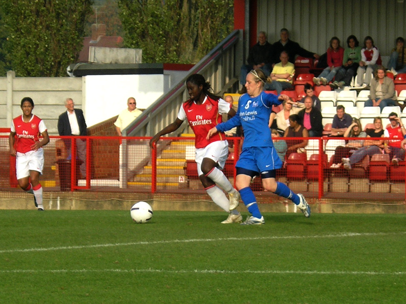 two men are playing soccer with fans watching