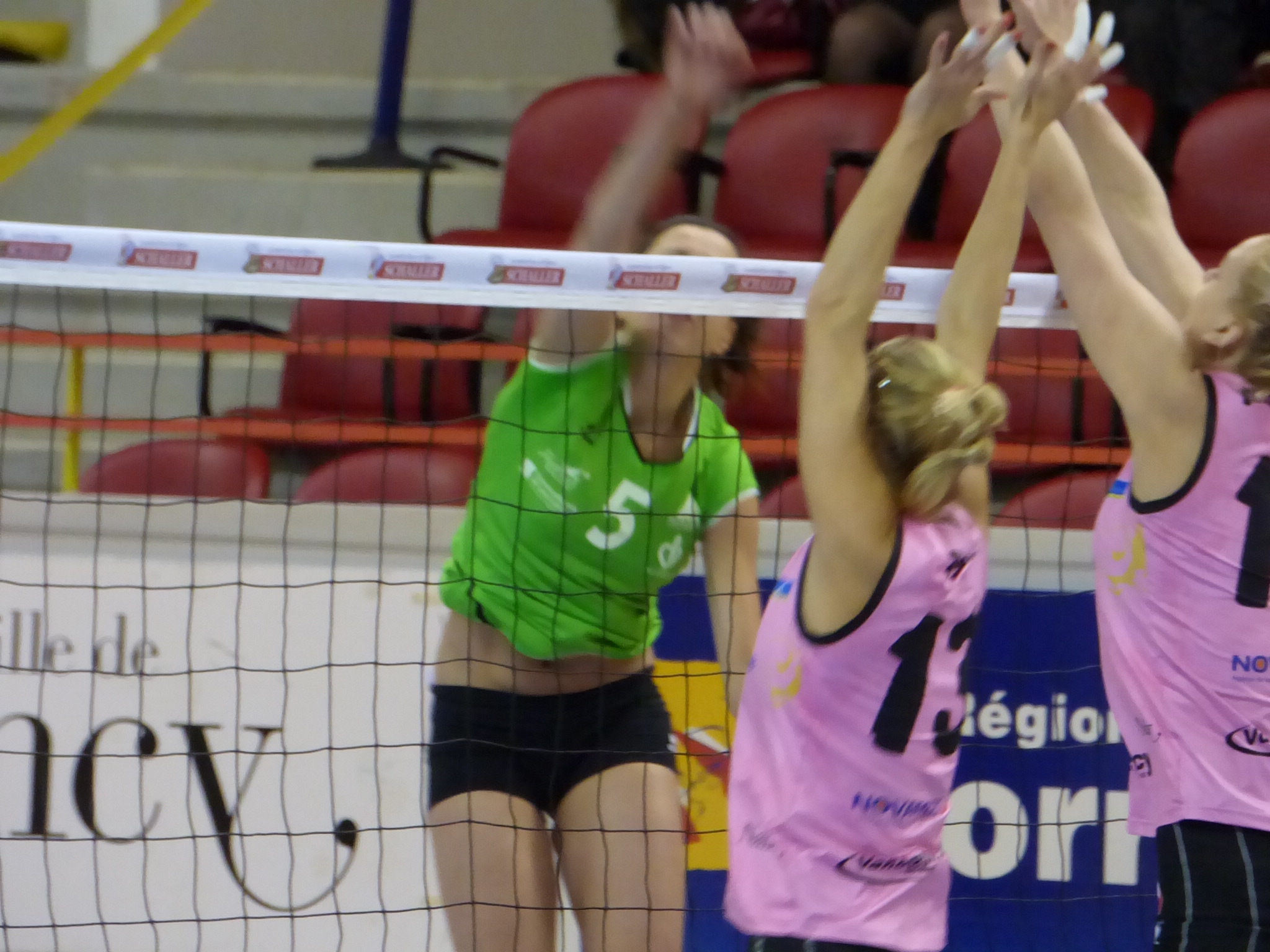 women wearing pink uniforms are trying to block a volleyball