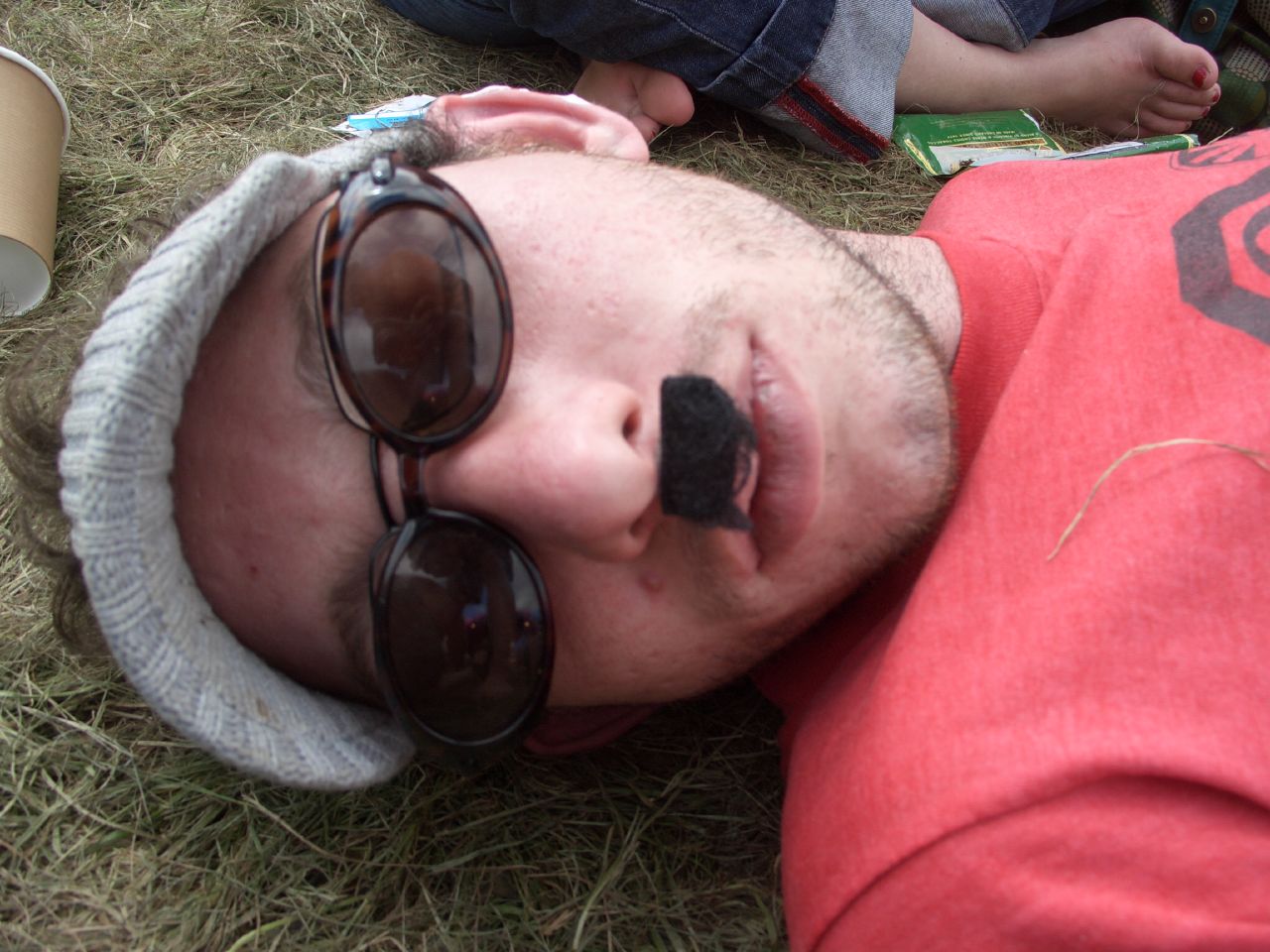 a man laying down on the ground wearing glasses