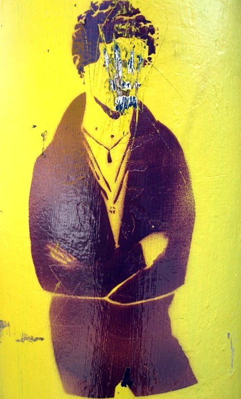 graffiti of a person wearing glasses on a yellow and black wall