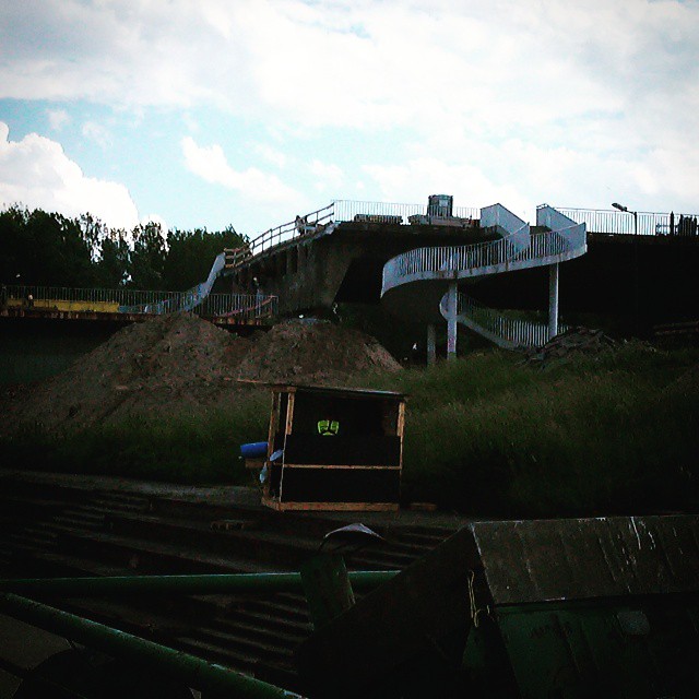 a dirt hill with some metal fence and a train in the background