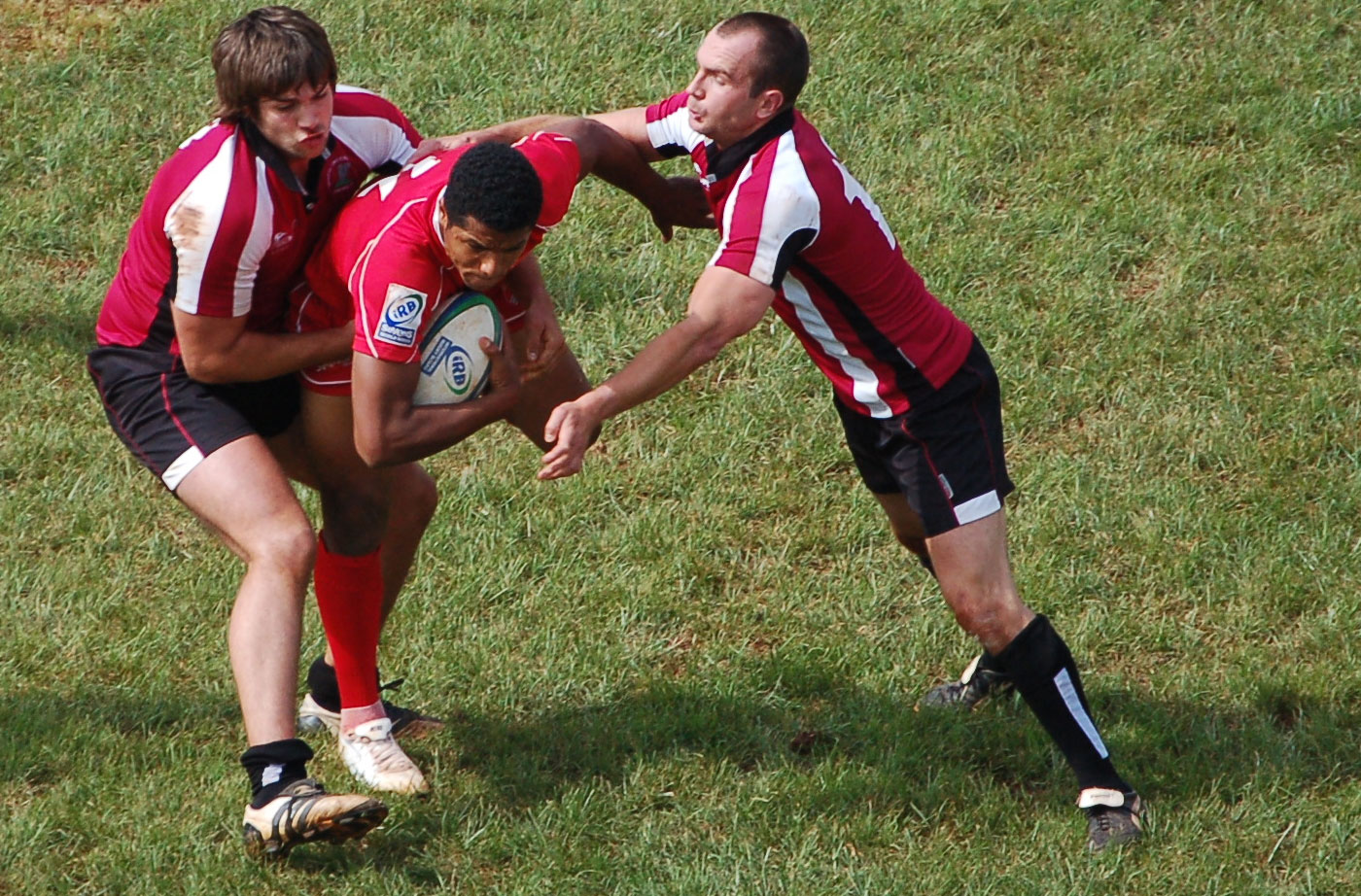 two men playing a game of rugby with a referee watching