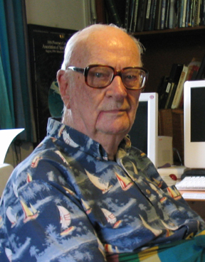 a older man wearing a patterned shirt sitting in a chair