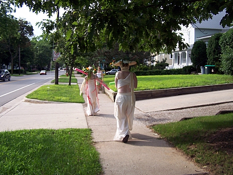 two women walking down the street, holding onto sticks