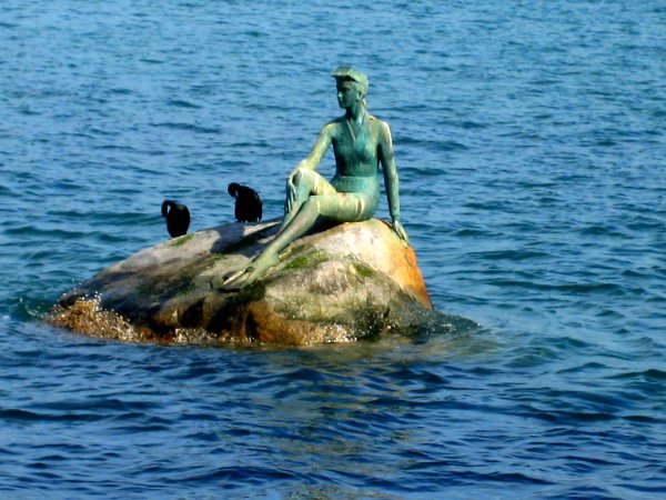 there is a statue of a person on a rock in the water