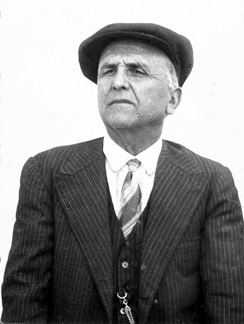 a man in a jacket and tie with a hat
