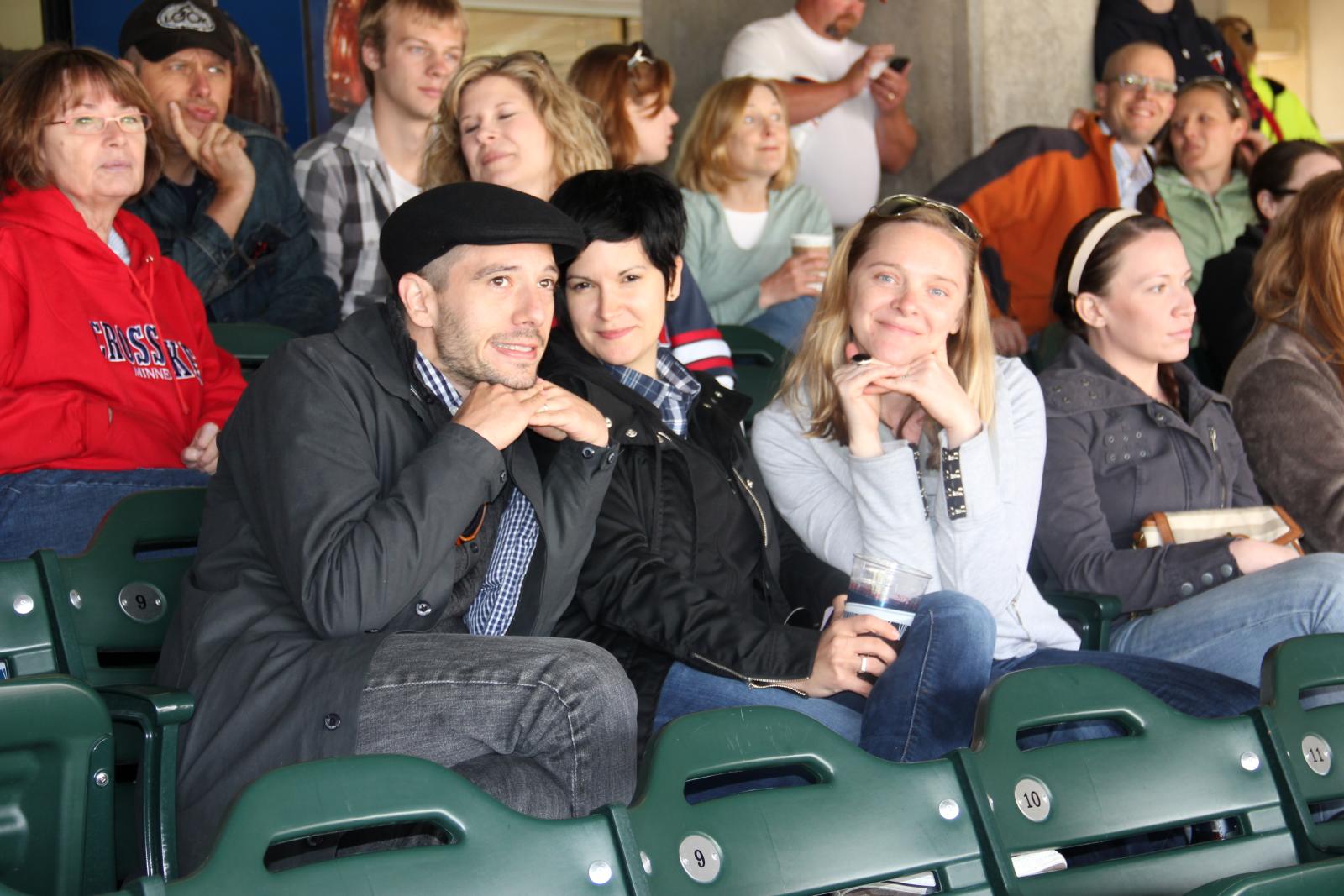several people sit in a stadium with a woman standing