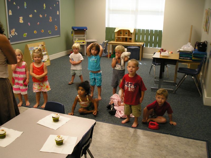 small children and their parents sitting around in an infant care center