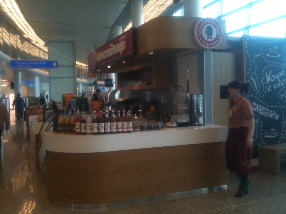 a woman standing by a counter filled with lots of drinks