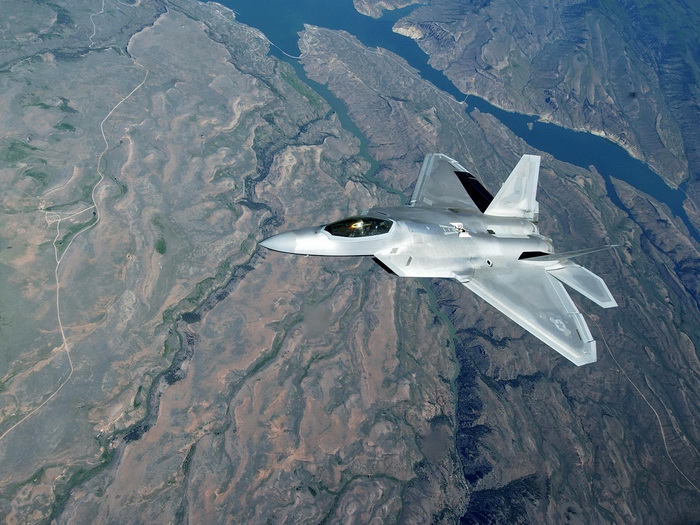a fighter jet flying through the sky over mountains