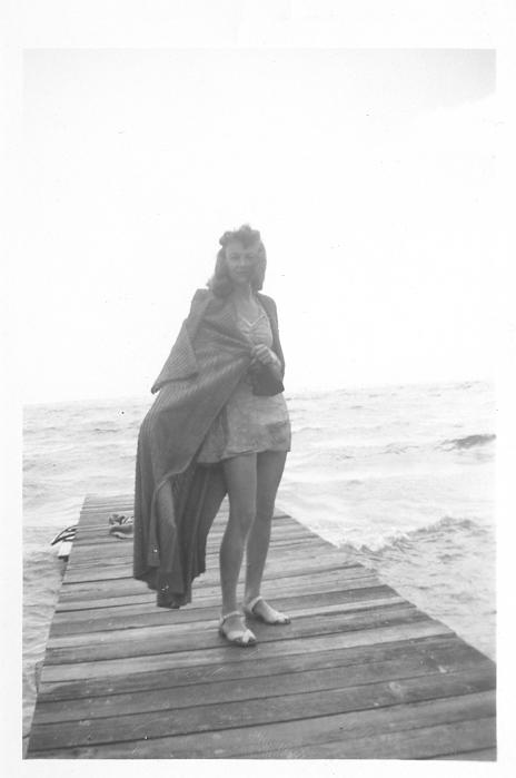 a woman is standing on a dock by the water