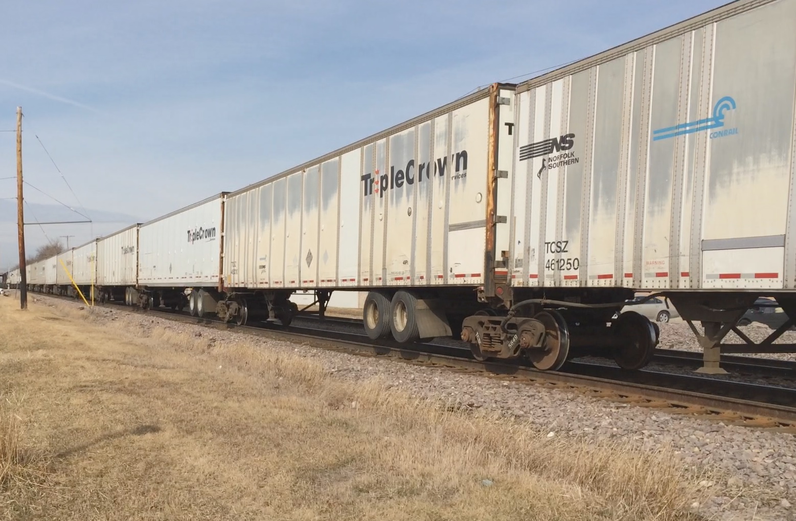 a train sitting on top of tracks by some dry grass