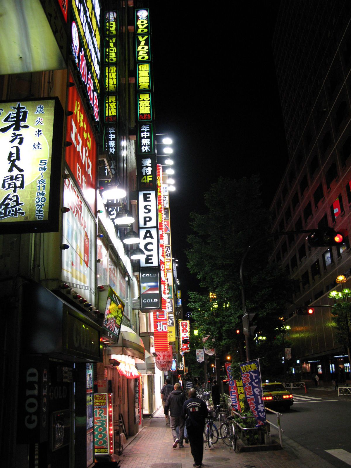 city scene with cars parked on street and large neon signs