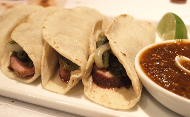 an entree features tortillas on a white plate with a dipping sauce