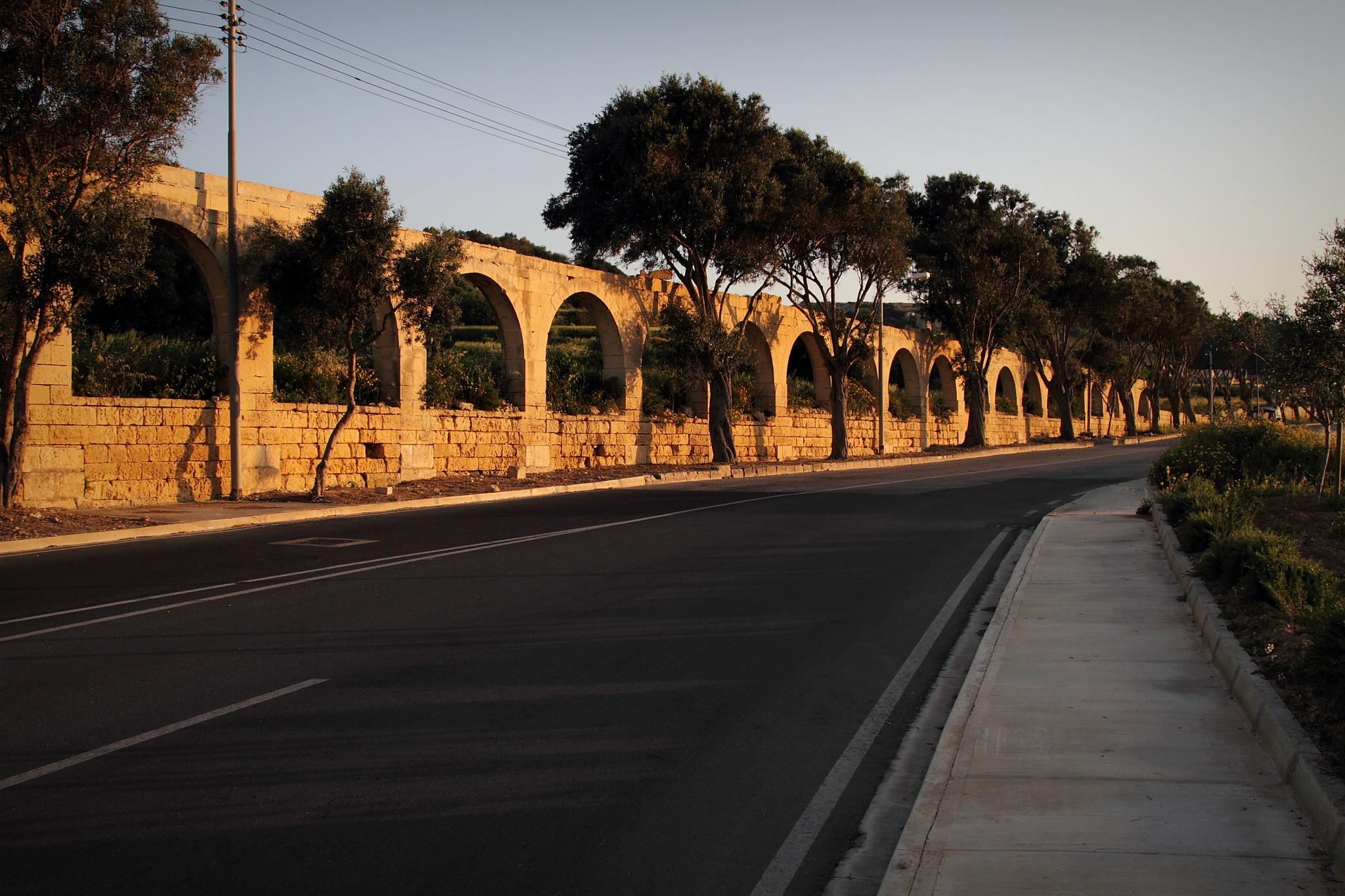 a view of the empty road near a stone wall