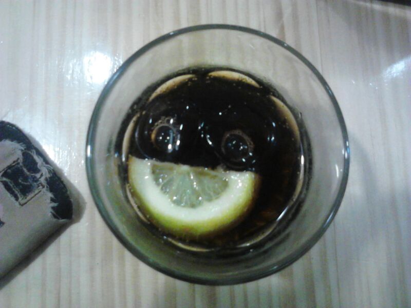 a cup with liquid and lemon sitting on top of a table