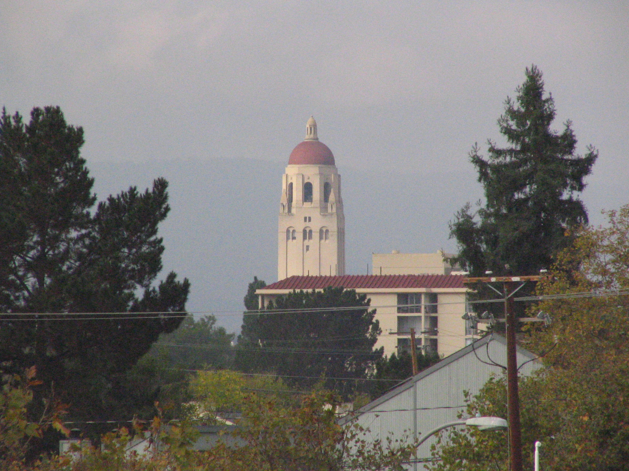 the building at the end of a city street with the belltower in the background