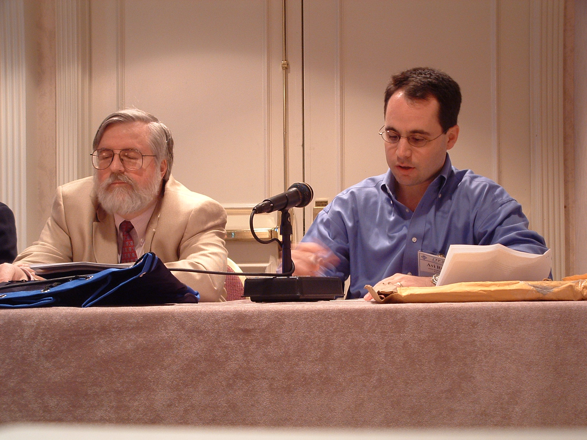 two men sitting at a table and one is on a laptop