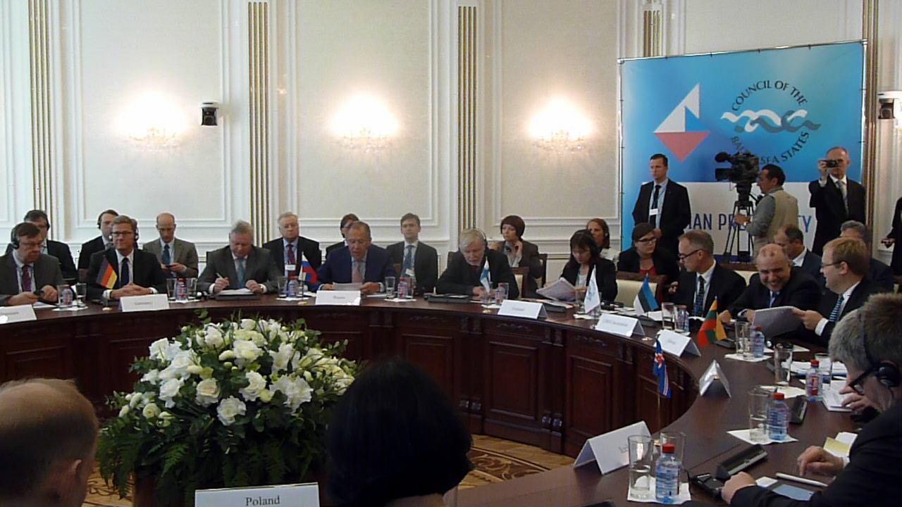 a group of people sitting at a round table with papers and microphones
